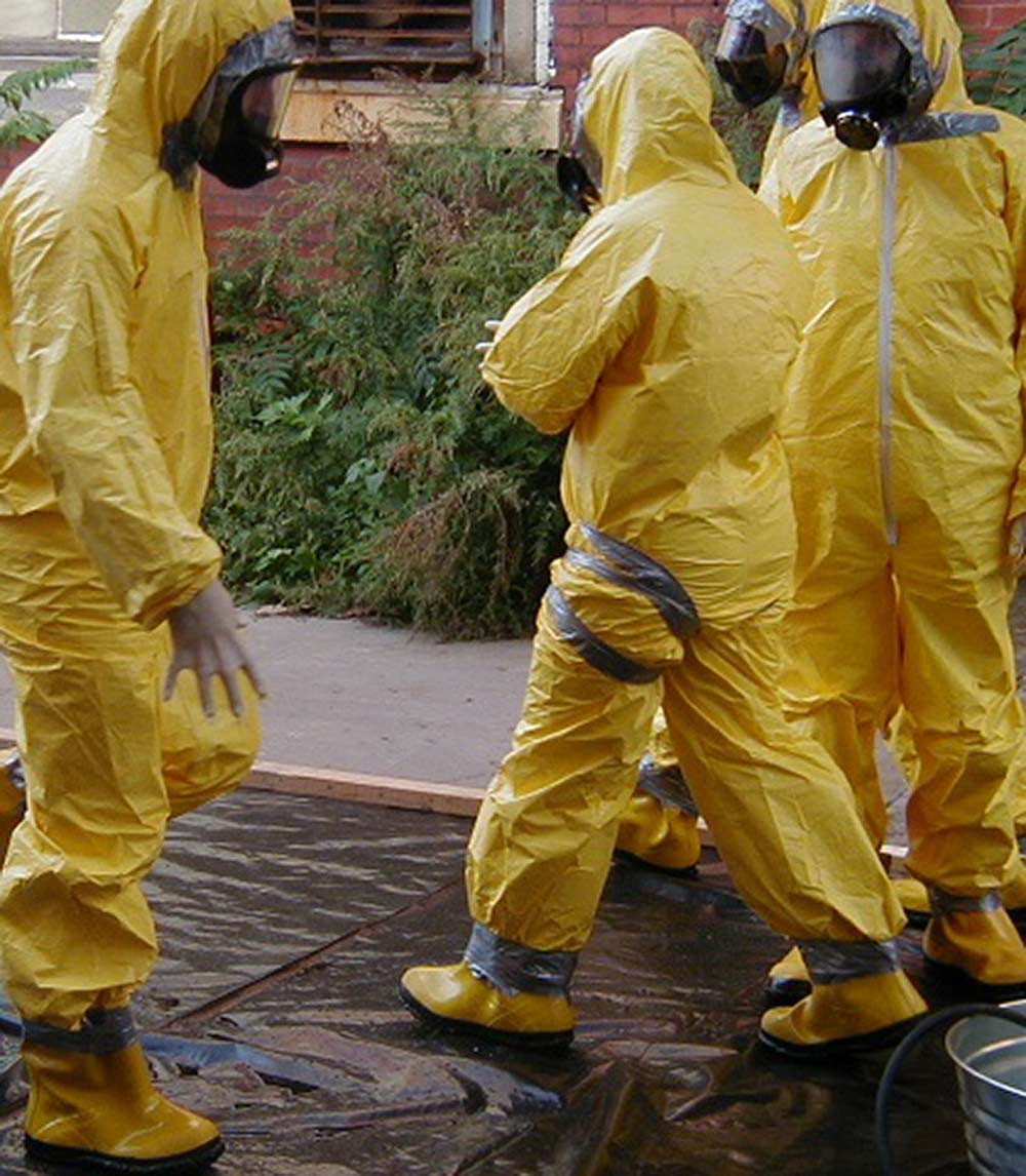 three workers in hazmat suits completing environmental remediation